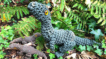 crocheted green dinosaurs surrounded by plants