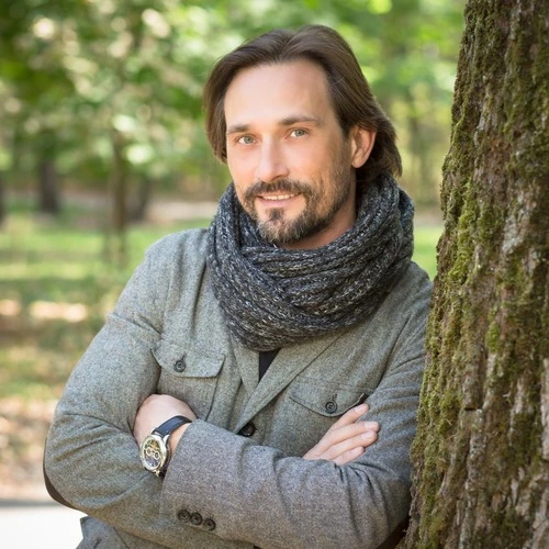 Head shot of handsome man leaning against a tree