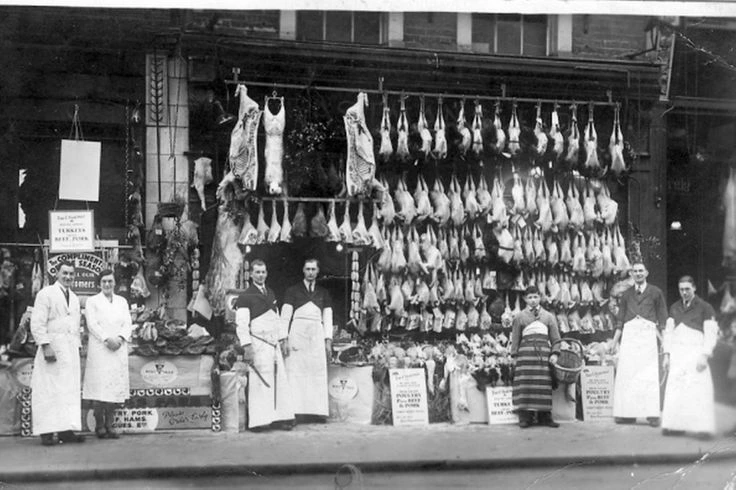 Victorian butcher shop with workers in aprons in black and white