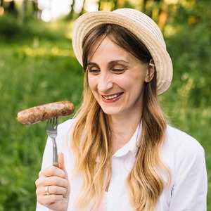 Young woman wearing a straw hat with sausage on a fork